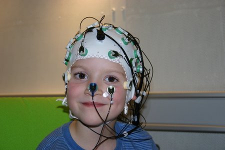 Ein Kind trägt eine EEG-Haube auf dem Kopf.